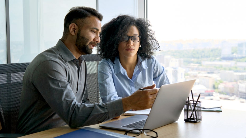 Two people look at a computer screen.