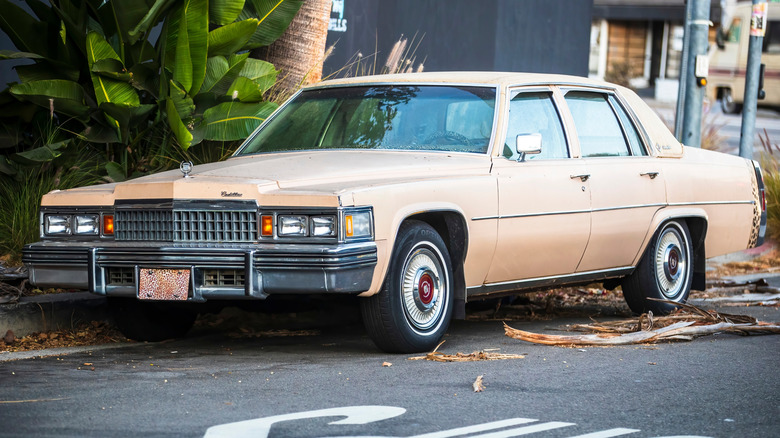 A beige 1978 Cadillac Fleetwood Brougham parked next to a curb.